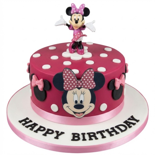 Round pink Minnie Mouse birthday cake with figurine, polka dots, and 'Happy Birthday' message.