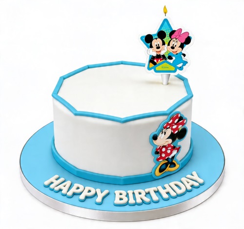 White birthday cake with blue trim, Minnie Mouse decoration, and Mickey and Minnie candle topper on a blue board.