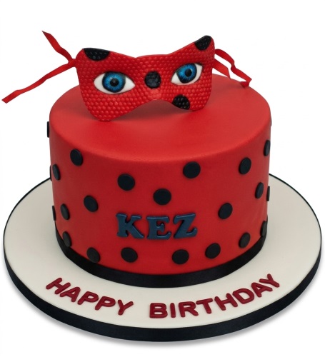 Red Miraculous Ladybug themed birthday cake with black polka dots and a mask topper.