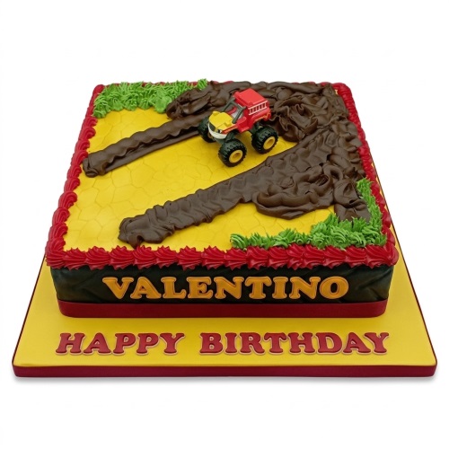 Monster truck themed birthday cake with mud tracks, green grass, and red piping on a yellow base.