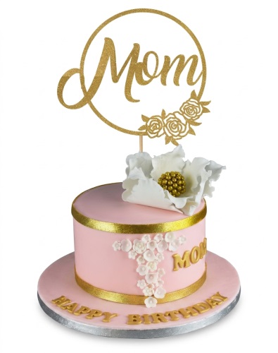 Elegant pink and gold birthday cake with a 'Mom' topper, white sugar flowers, and 'Happy Birthday' message.