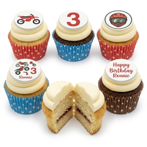 Six cupcakes with white icing and motorbike, helmet, and number 3 toppers. One cupcake is cut in half revealing jam filling.