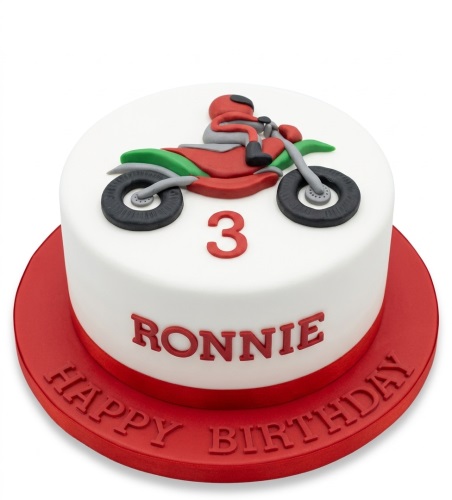 Round white birthday cake with 3D red and green motorbike, custom age, and personalised name.