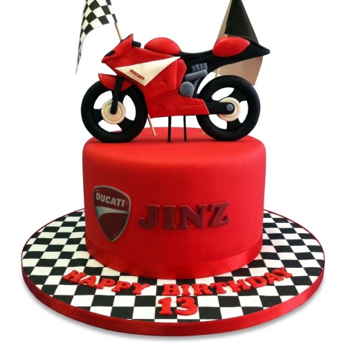 Red motorcycle birthday cake with a Ducati bike topper, checkered flag, and racing board.