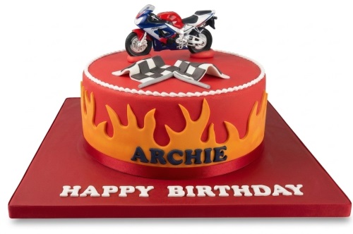 Red birthday cake with orange flames, a model motorcycle, and a checkered flag topper.