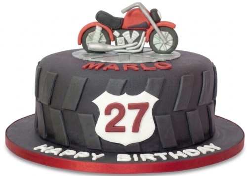 Round dark grey motorcycle birthday cake with red bike topper and tyre tread texture, custom age plaque.