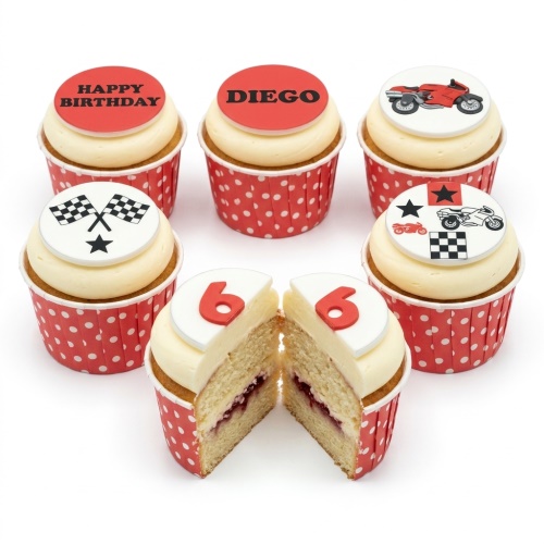 Six vanilla cupcakes with red polka dot cases, white frosting, and racing theme toppers including motorbikes, checkered flags, and a custom age '6'.