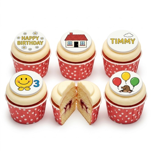 Selection of kids birthday cupcakes with white icing and red polka dot cases, featuring various custom toppers including 'Happy Birthday', a house, a smiley face with '3', a mole with balloons, and a name 'Timmy'.