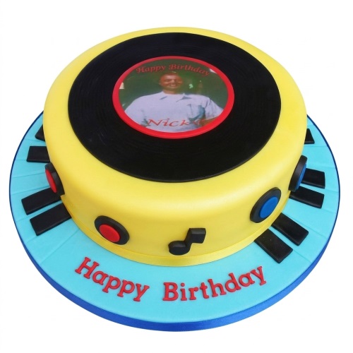Round yellow music theme birthday cake with a record player design, edible photo, piano keys, and music note decorations.
