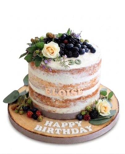 Naked birthday cake with fresh berries, white roses, green leaves, and a custom age topper.