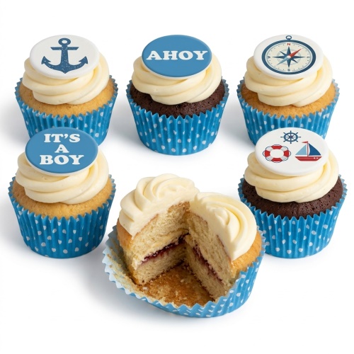Selection of nautical themed cupcakes with blue and white toppers, including an anchor, compass, sailboat, and 'It's A Boy' message, in blue polka dot wrappers.