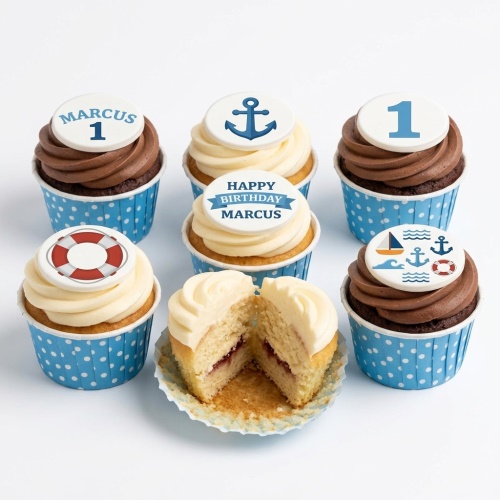Cupcakes with nautical designs: anchors, lifebuoys, sailboat. Blue polka dot wrappers, custom age and personalised message.