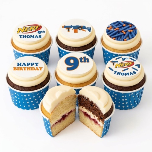 A set of Nerf theme birthday cupcakes with various edible toppers including a Nerf logo, a blaster, and darts, in blue polka dot cases.