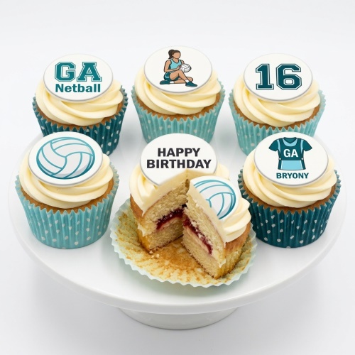 A selection of netball-themed birthday cupcakes with white frosting and teal decorations, including a netball player, netball, GA Netball logo, and custom age topper.