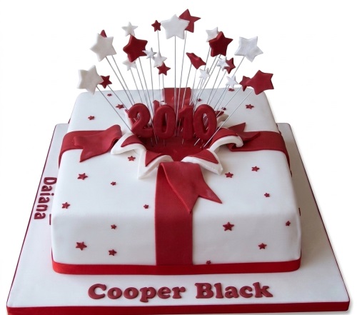 White square gift box birthday cake with red ribbon, bow, and exploding red and white star toppers with a custom age.