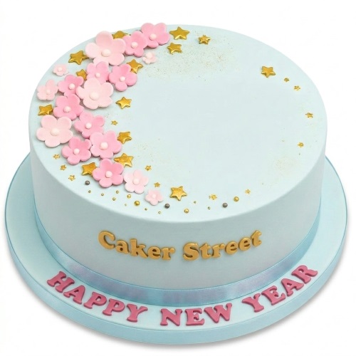 Light blue round cake with pink sugar flowers, gold stars, and edible sprinkles.