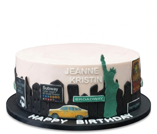 Round New York City theme birthday cake with Statue of Liberty, taxi, subway sign, and Broadway show posters.