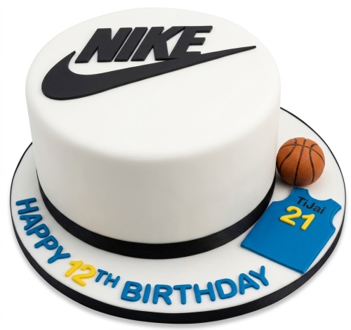 White round birthday cake with black Nike logo, miniature basketball, and blue jersey with custom name and number.