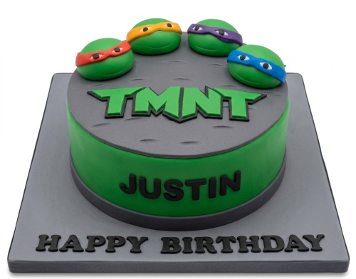 Round green and grey TMNT birthday cake with four turtle head toppers and a custom name.