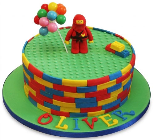 Lego-style birthday cake with red Ninjago character, balloons, and building blocks.