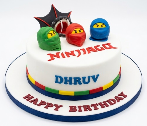 White round Ninjago theme birthday cake with red, green, blue ninja figures and a bat-wing snake decoration.