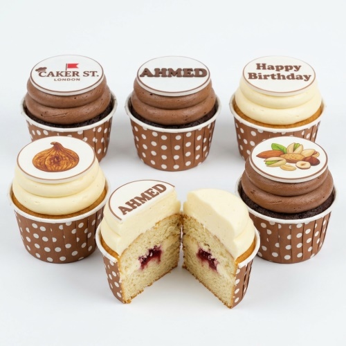 Assortment of personalised birthday cupcakes with custom edible toppers, including a logo, name, and fruit/nut designs.