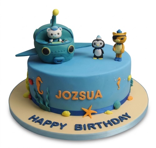 Blue Octonauts themed birthday cake with submarine, penguin, and cat characters, decorated with seahorses and shells.
