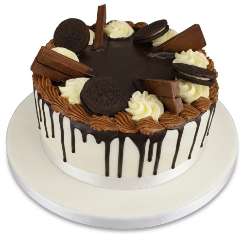 Round white cake with chocolate drip, topped with Oreo cookies, chocolate bars, and piped buttercream.