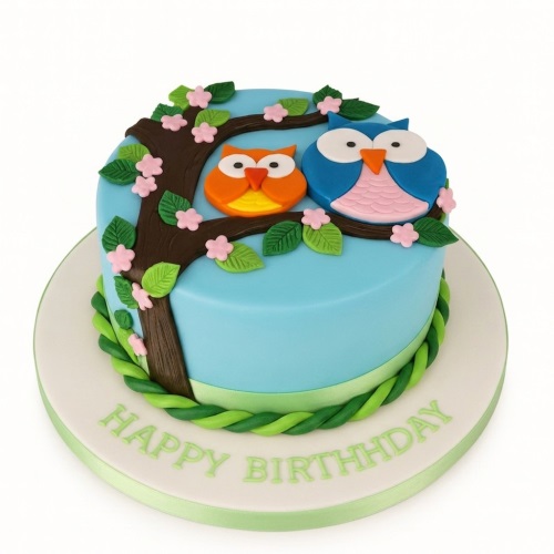 Round blue birthday cake with two fondant owls on a tree branch and "Happy Birthday" message.