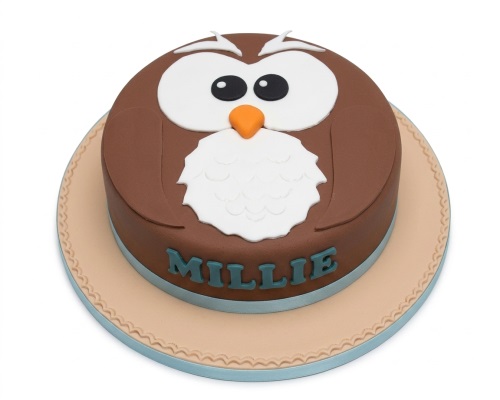 Round brown owl birthday cake with white face, orange beak, and personalised name on the side.