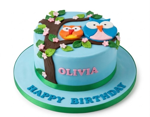 Light blue round birthday cake with two fondant owls on a tree branch with pink flowers and green leaves.