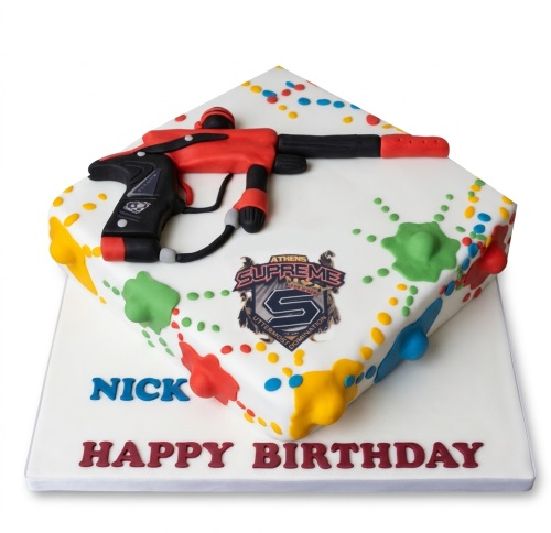 Square white birthday cake with a red and black paintball gun, colourful paint splatters, and a custom message.