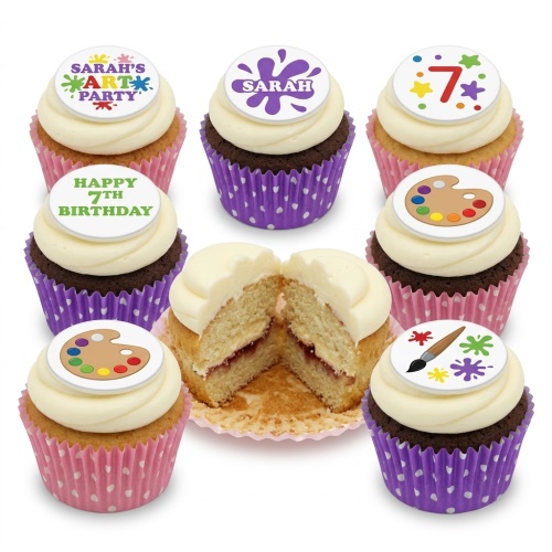 White frosted cupcakes with art-themed toppers, including paint palettes, paintbrushes, and paint splatters.