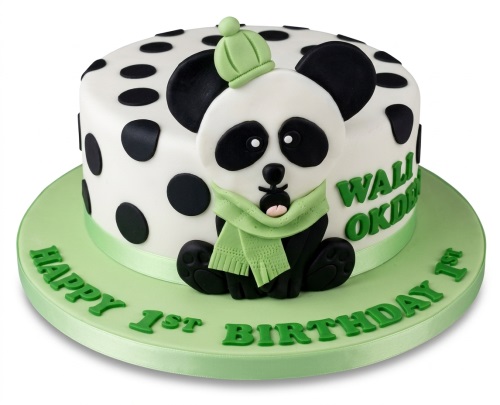 White round cake with black polka dots, a 3D panda figure wearing a green hat and scarf, and a green "Happy 1st Birthday" message on the board.
