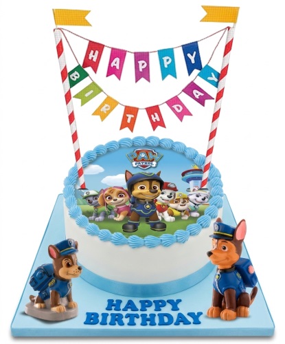 Round white Paw Patrol birthday cake with Chase and other characters on top, blue trim, and two Chase figurines on the cake board.