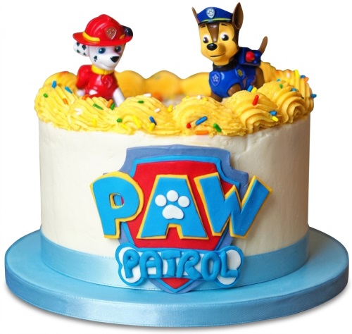 Round white Paw Patrol birthday cake with Marshall and Chase figurines, yellow swirls, and sprinkles.