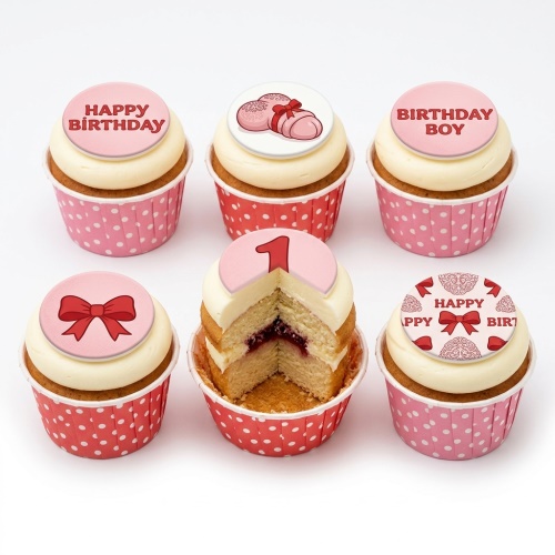 Six cupcakes with white icing, red polka dot cases, and edible toppers featuring baby booties, bows, 'Happy Birthday', 'Birthday Boy', and the number '1'.