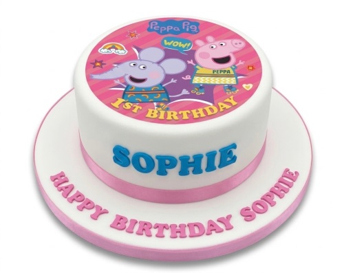 Round white Peppa Pig 1st birthday cake with edible image topper and pink ribbon.