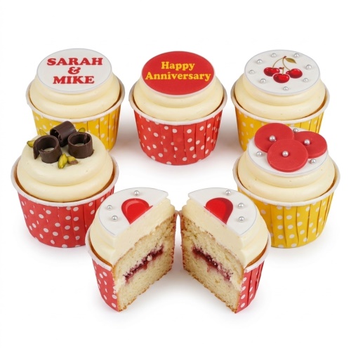 Assortment of anniversary cupcakes with red and white decorations, including hearts, cherries, and custom messages.