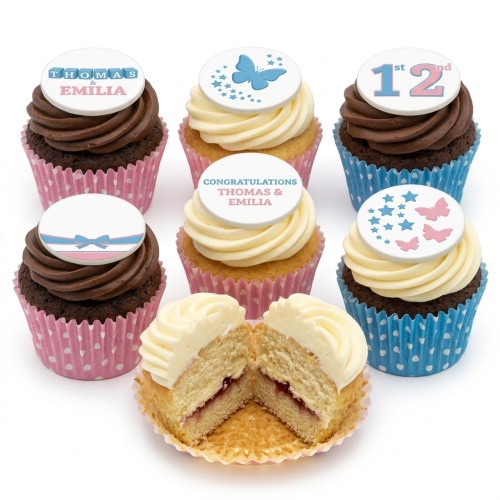 Baby shower cupcakes with pink and blue butterfly, star, and baby block toppers, some with a bow, in pink and blue polka dot wrappers.