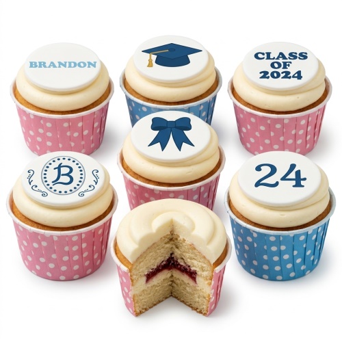 Selection of vanilla cupcakes with cream frosting and customisable edible toppers, including a graduation cap, a bow, an initial 'B', 'CLASS OF 2024', and the number '24'. One cupcake is cut open revealing a jam filling.