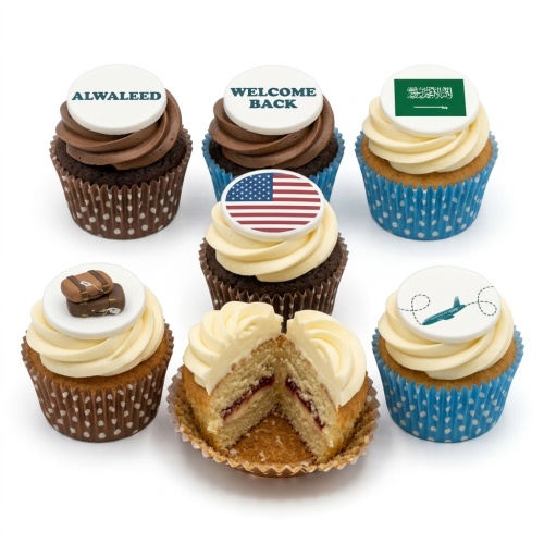 Assorted cupcakes with travel theme toppers, including flags, suitcases, and an airplane.