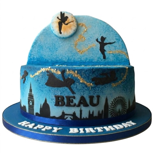 Two-tier Peter Pan themed birthday cake with London skyline and flying silhouettes, blue and gold colours, personalised name.