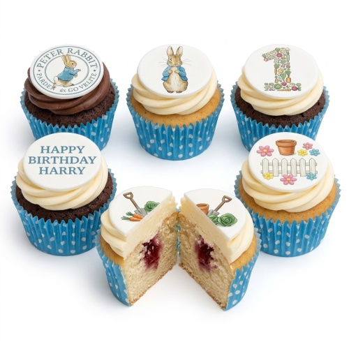 Peter Rabbit themed cupcakes with white and chocolate icing, blue polka dot cases, and edible toppers including Peter Rabbit, garden items, and a vegetable number one.
