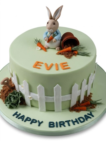Round light green Peter Rabbit birthday cake with a rabbit figure, carrots, a fence, and an overturned pot.