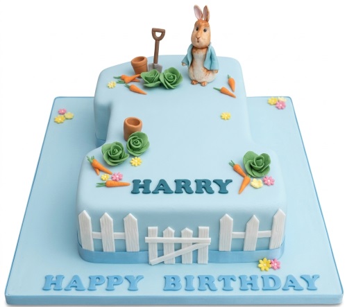 Light blue number one shaped cake with Peter Rabbit figurine, carrots, cabbages, and picket fence.