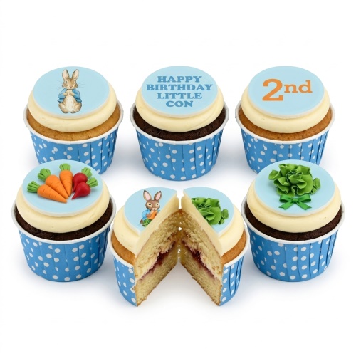 Peter Rabbit themed cupcakes with character, carrot, and ruffle toppers in blue polka dot wrappers.