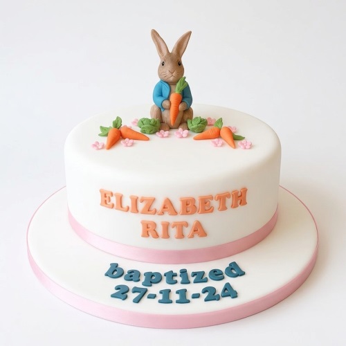 White christening cake with Beatrix Potter Peter Rabbit figurine, sugar carrots, and pink flowers.