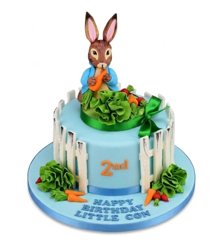 Peter Rabbit themed birthday cake with a rabbit figure, garden decorations, and a custom age topper.