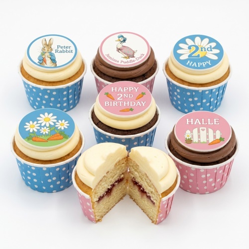 A selection of Peter Rabbit and Jemima Puddle-Duck cupcakes with custom age and name toppers, in blue and pink polka dot wrappers.